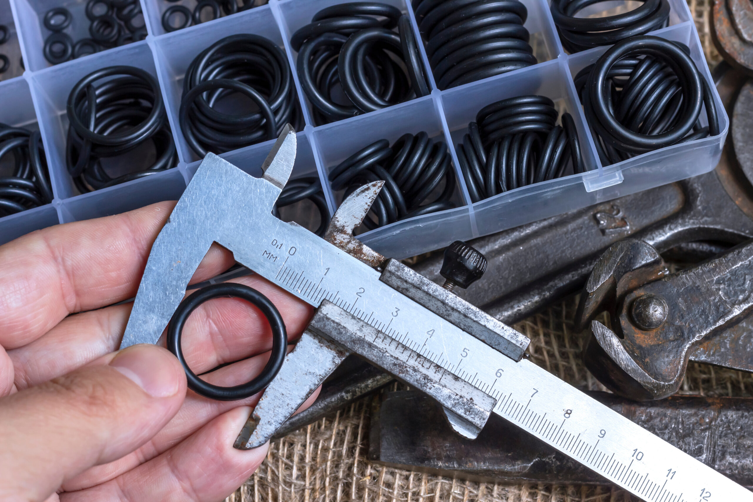 A man measures the outside diameter of an O-ring with calipers