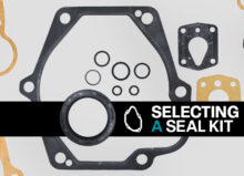 Components in a piston pump seal kit, including O-rings, gaskets, and washers on a gray background. A black banner with the words "Selecting a Seal Kit" appears at the forefront of the image.