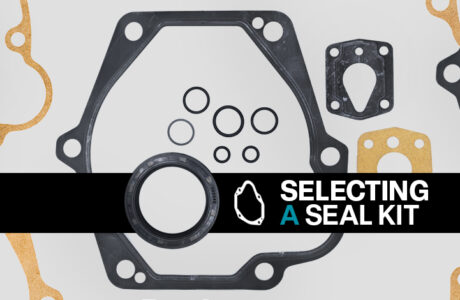 Components in a piston pump seal kit, including O-rings, gaskets, and washers on a gray background. A black banner with the words "Selecting a Seal Kit" appears at the forefront of the image.